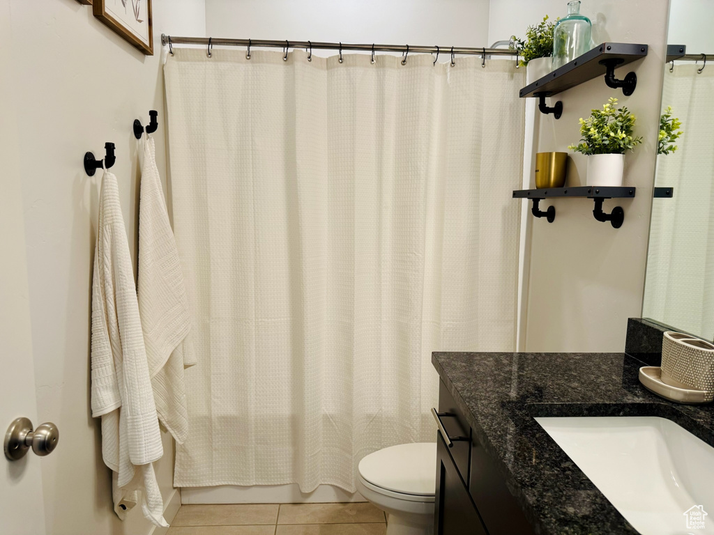 Full bathroom featuring tile patterned floors, vanity, toilet, and shower / tub combo with curtain