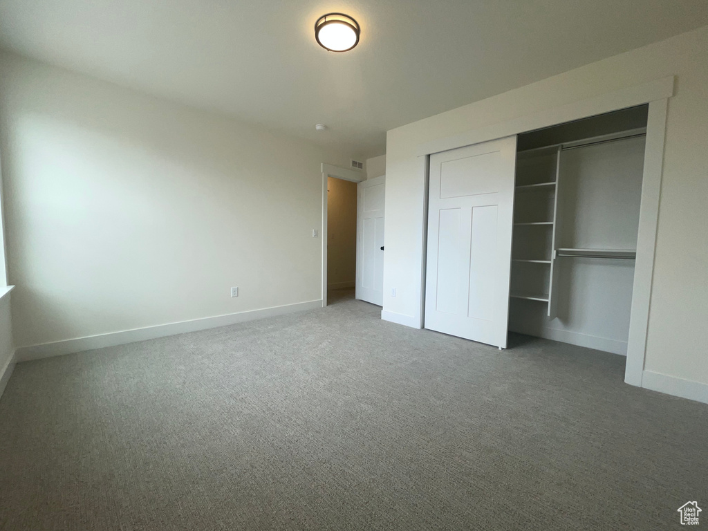 Unfurnished bedroom featuring a closet, baseboards, and carpet