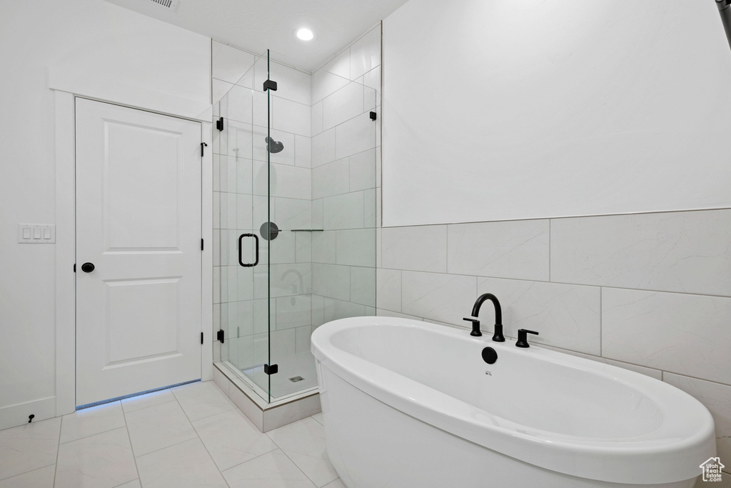 Full bathroom with tile walls, a stall shower, and a soaking tub