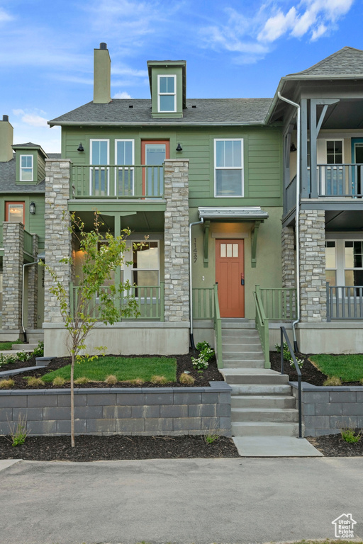 View of front of property with a balcony, a chimney, and a shingled roof