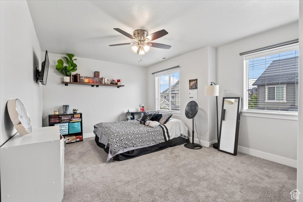 Carpeted bedroom featuring multiple windows, baseboards, and ceiling fan
