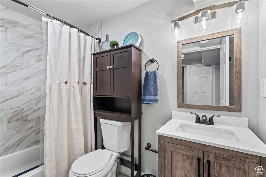 Bathroom featuring toilet, shower / bath combo, and vanity