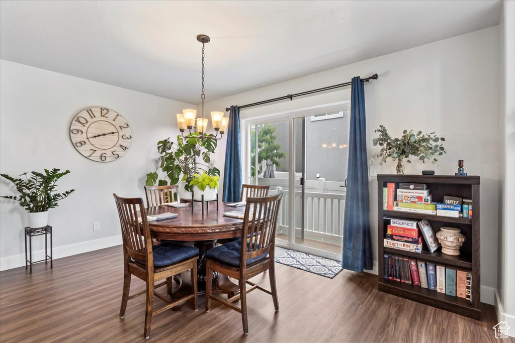 Dining space featuring wood finished floors, a chandelier, and baseboards