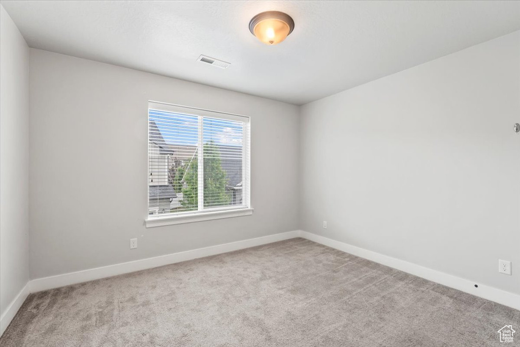 Carpeted spare room featuring baseboards