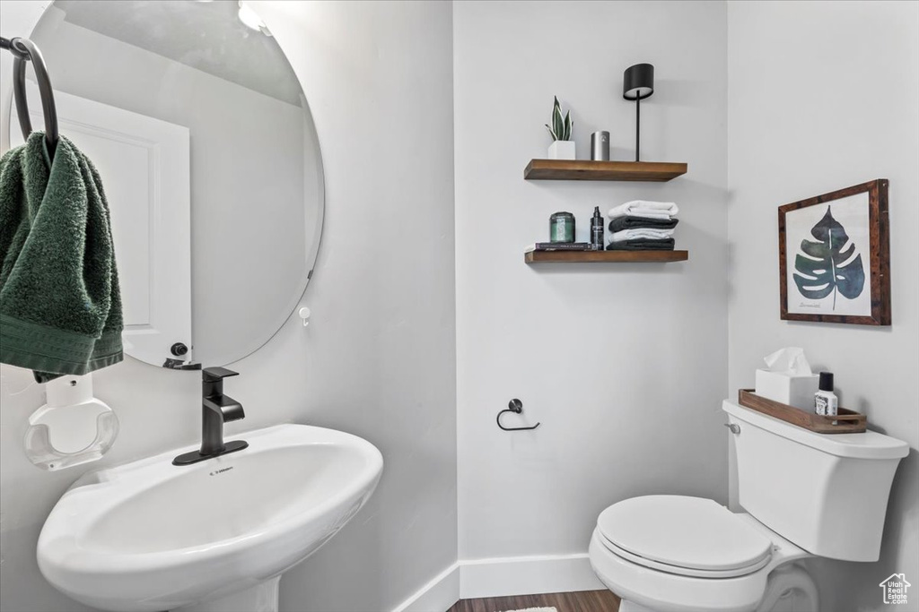Bathroom featuring a sink, toilet, baseboards, and wood finished floors