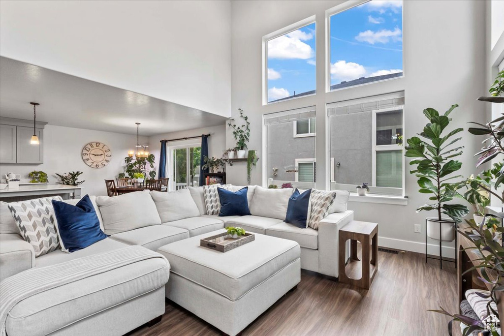Living area with dark wood-type flooring, a high ceiling, a chandelier, and baseboards