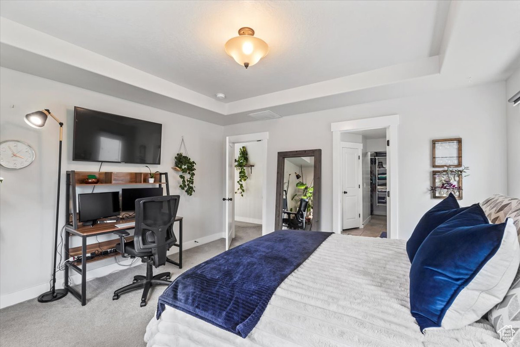 Bedroom featuring carpet, baseboards, a raised ceiling, and an office area