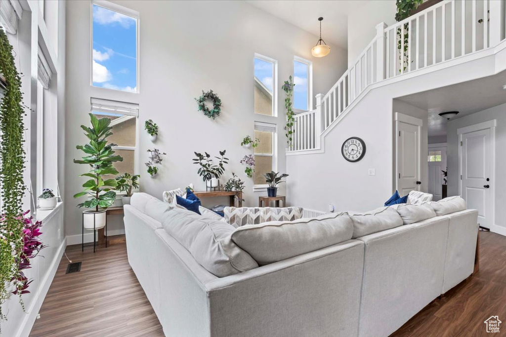Living area featuring healthy amount of natural light, a high ceiling, dark wood finished floors, and baseboards