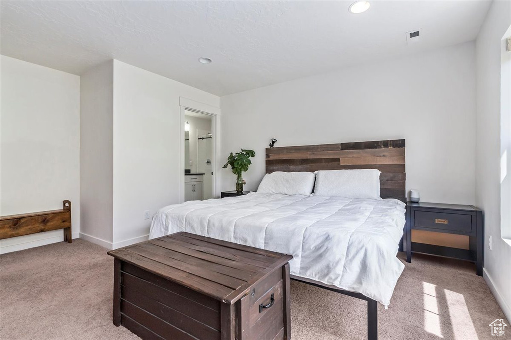 Bedroom with light colored carpet, recessed lighting, baseboards, and connected bathroom