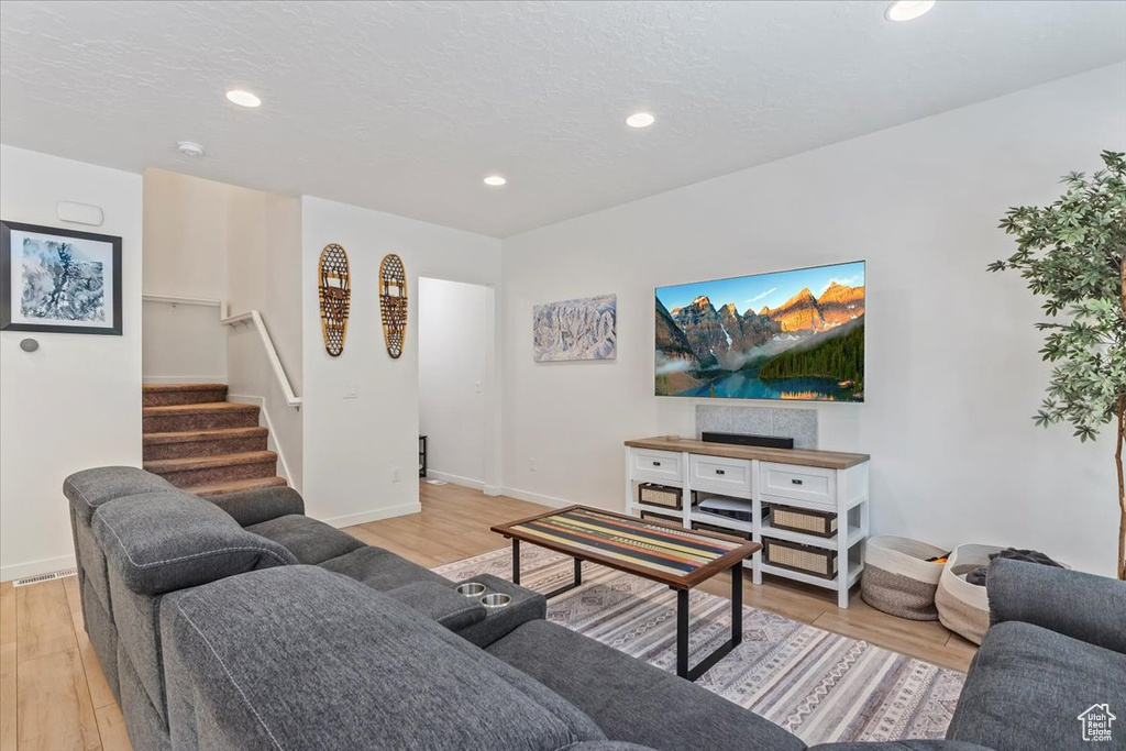 Living room featuring light wood finished floors, recessed lighting, stairs, and baseboards