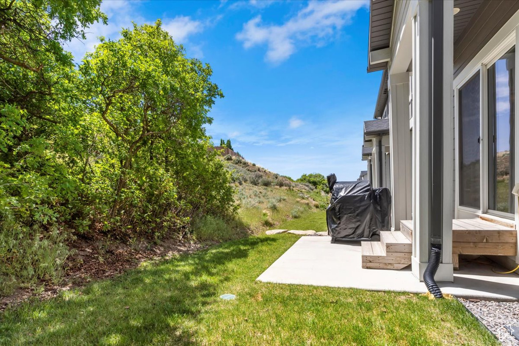 View of green lawn featuring a patio area and a mountain view