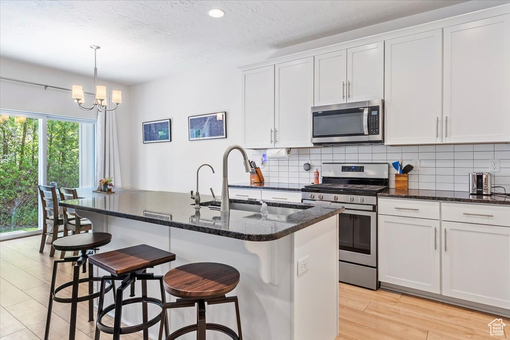 Kitchen with stainless steel appliances, a sink, decorative backsplash, a chandelier, and recessed lighting