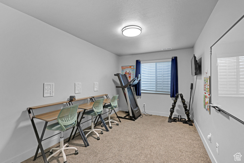 Carpeted home office with baseboards and a textured ceiling