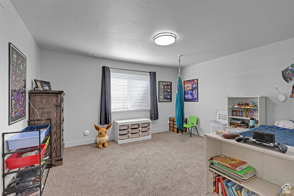 Bedroom featuring carpet, a textured ceiling, and baseboards