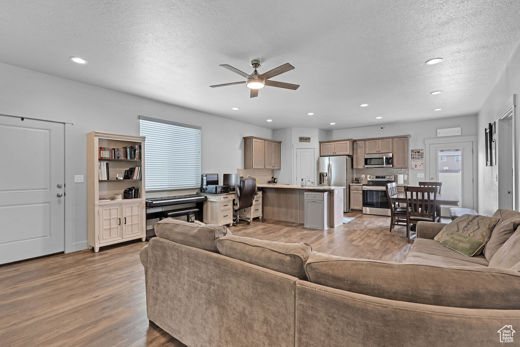 Living room with light wood-style flooring, a ceiling fan, a textured ceiling, and recessed lighting