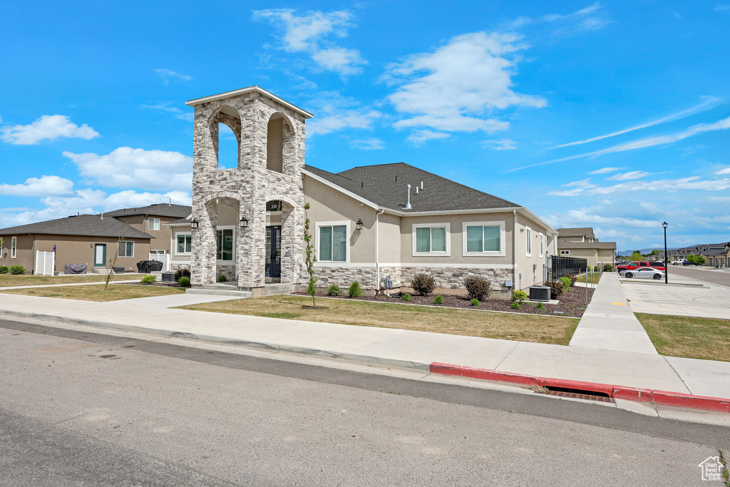 View of front of property with stucco siding, stone siding, and central AC