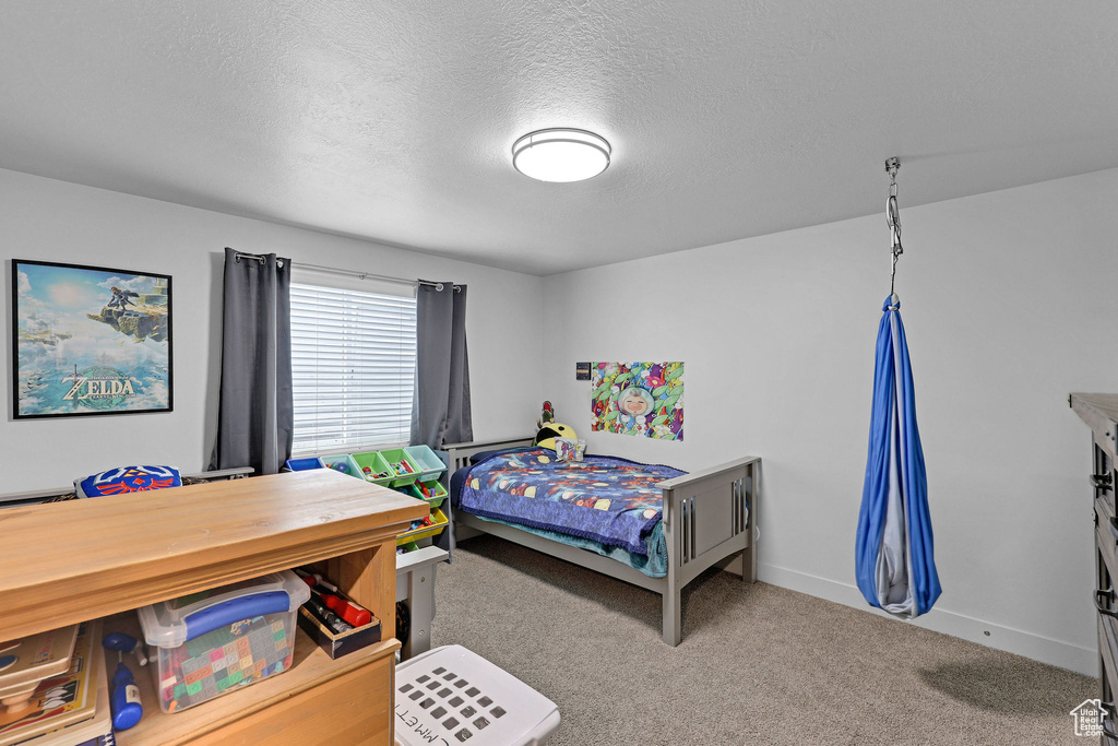 Carpeted bedroom featuring a textured ceiling and baseboards