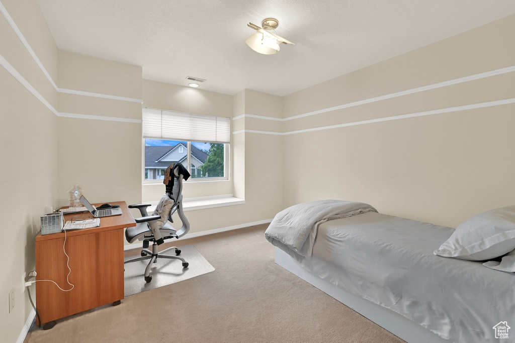 Bedroom featuring light colored carpet, an office area, and baseboards