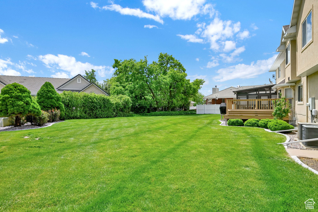View of grassy yard with cooling unit and a sunroom
