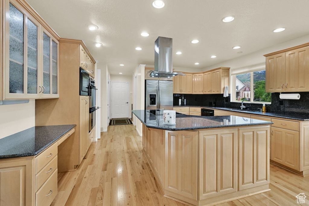 Kitchen with black appliances, light brown cabinets, island range hood, a sink, and a center island