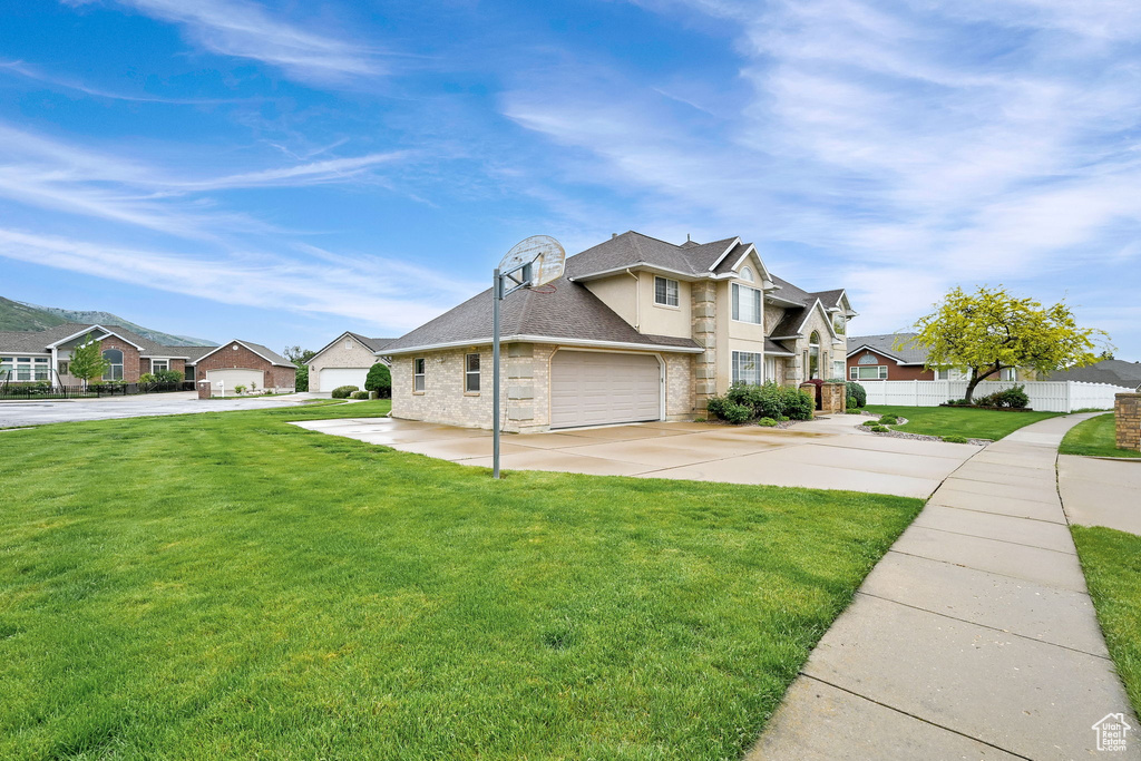 Traditional-style house featuring a residential view, driveway, stone siding, and a garage