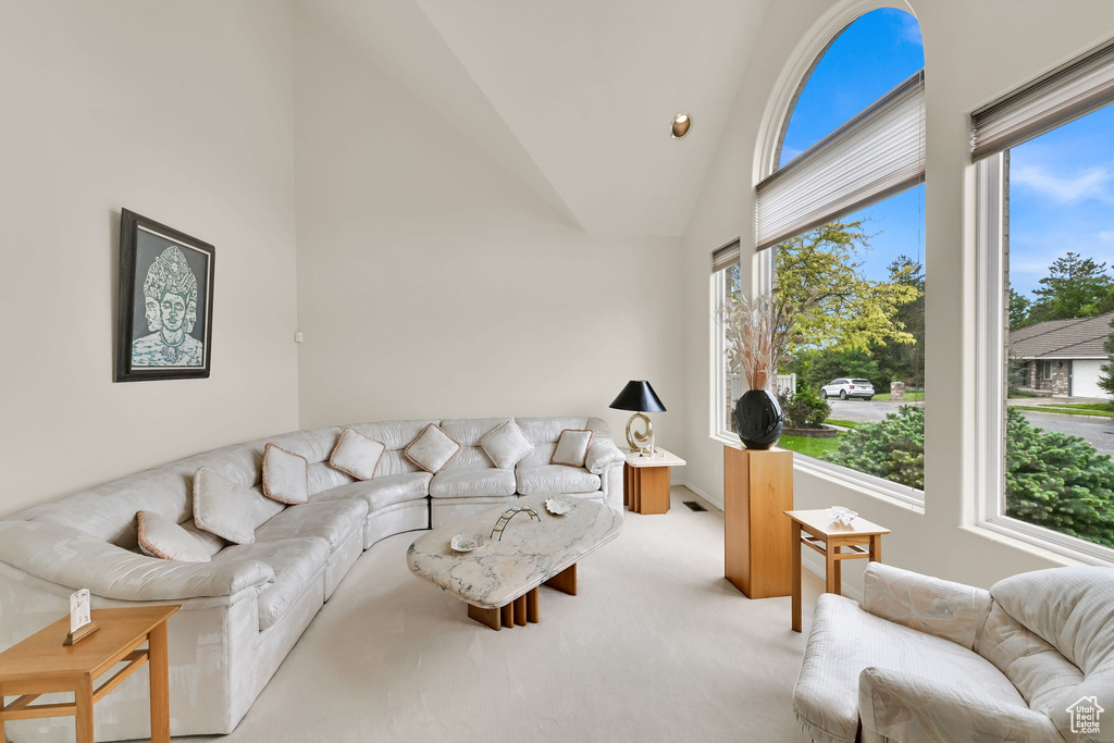 Living room featuring plenty of natural light, light colored carpet, and high vaulted ceiling