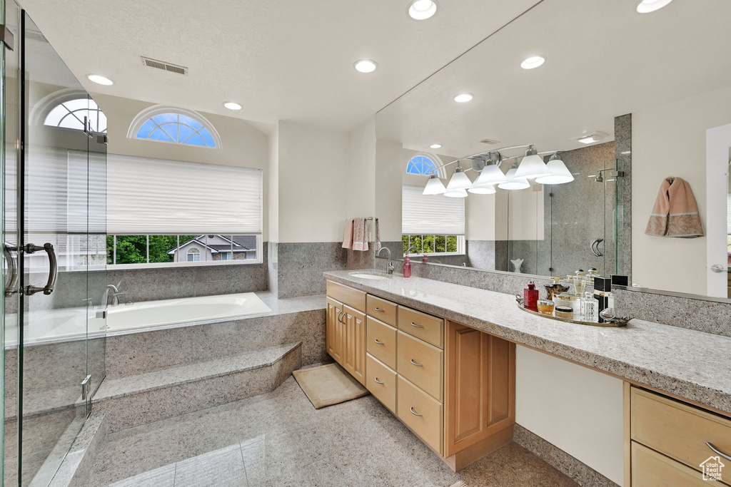 Bathroom featuring healthy amount of natural light, vanity, a shower stall, a garden tub, and recessed lighting