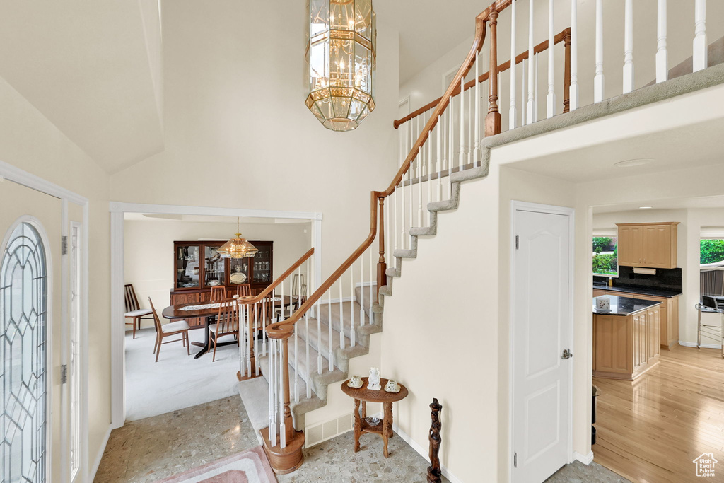 Foyer featuring a chandelier, a high ceiling, stairs, and baseboards