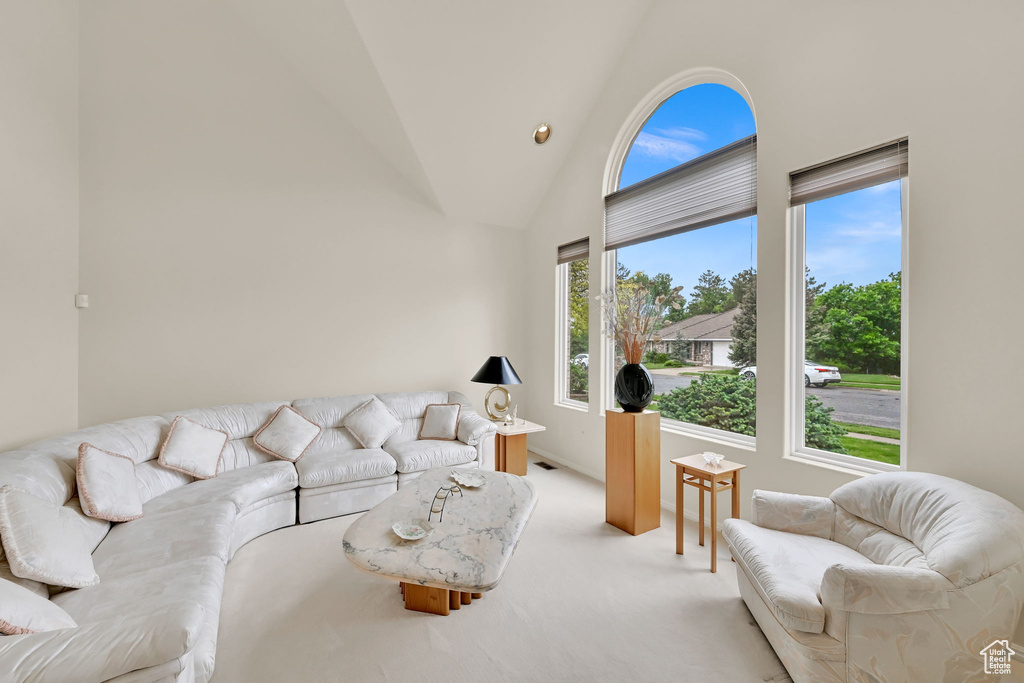 Living room featuring high vaulted ceiling and light colored carpet