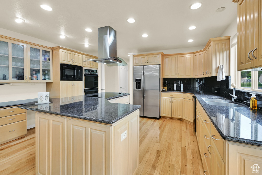 Kitchen with black appliances, island exhaust hood, a sink, light brown cabinetry, and light wood-style floors