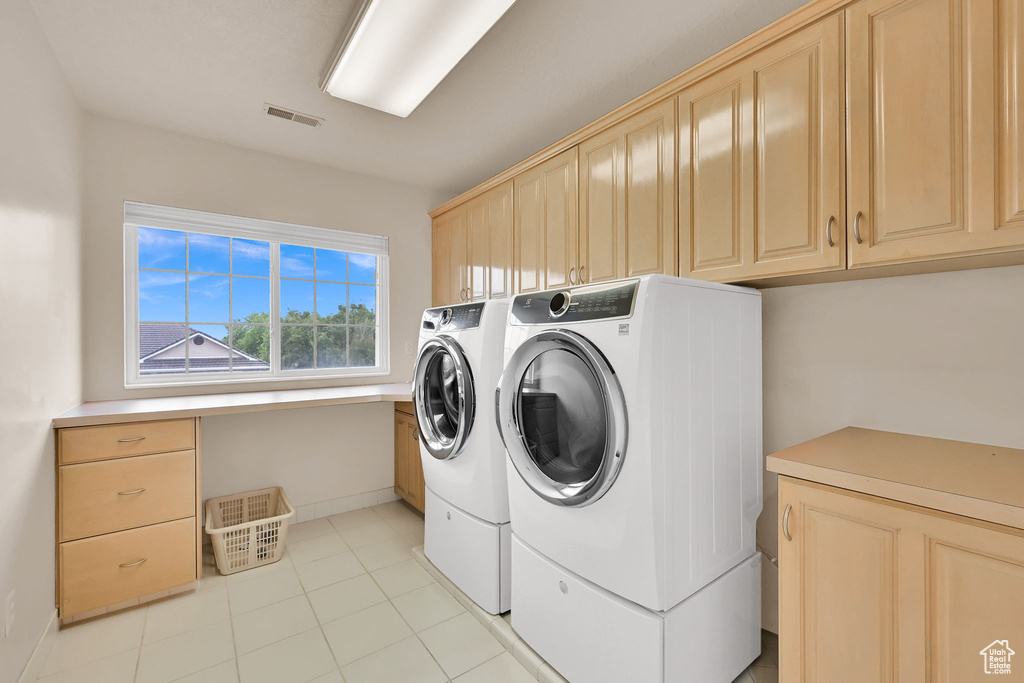 Clothes washing area featuring cabinet space, independent washer and dryer, baseboards, and light tile patterned floors
