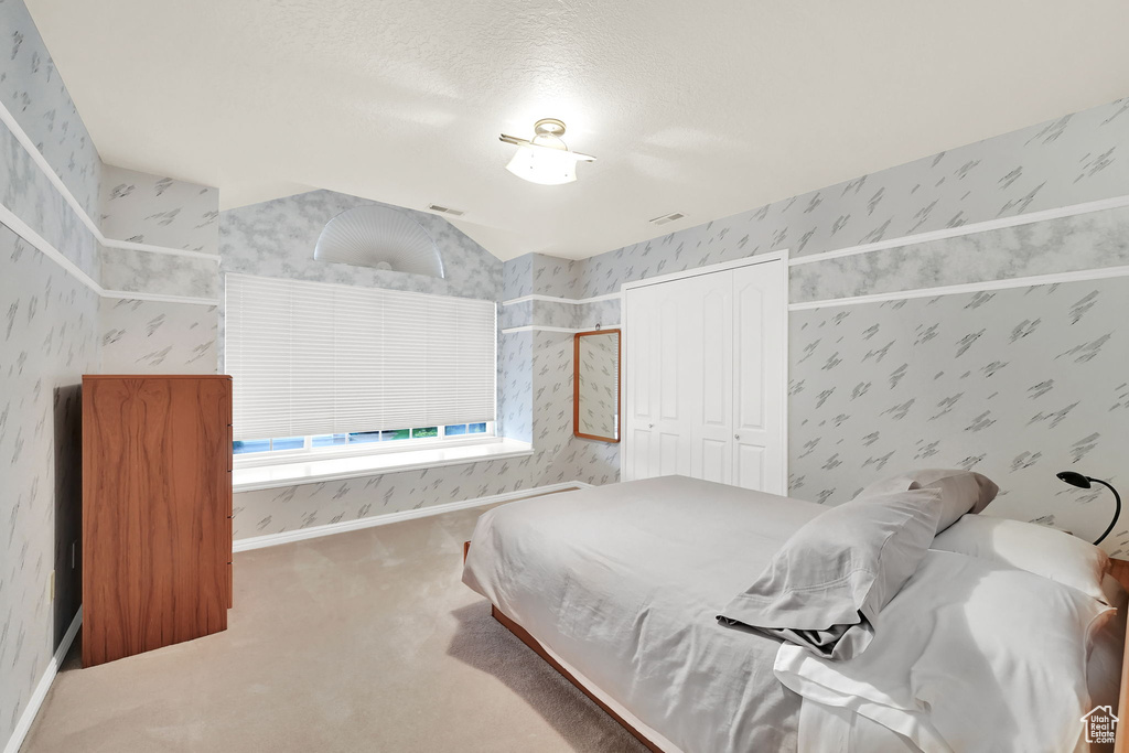 Carpeted bedroom featuring wallpapered walls and a closet