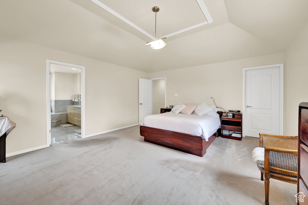 Carpeted bedroom with baseboards, connected bathroom, and a tray ceiling