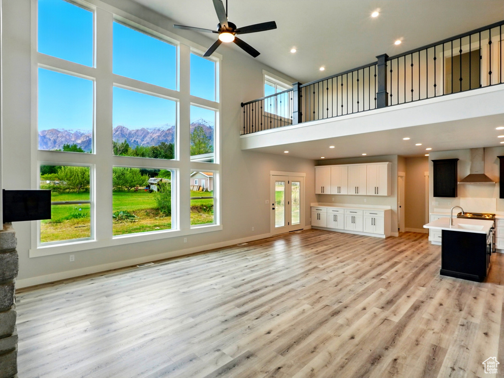 Unfurnished living room with a towering ceiling, a ceiling fan, baseboards, recessed lighting, and a mountain view