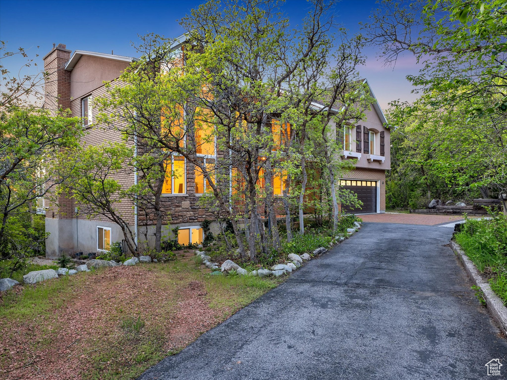 View of front of home with an attached garage, asphalt driveway, and stucco siding