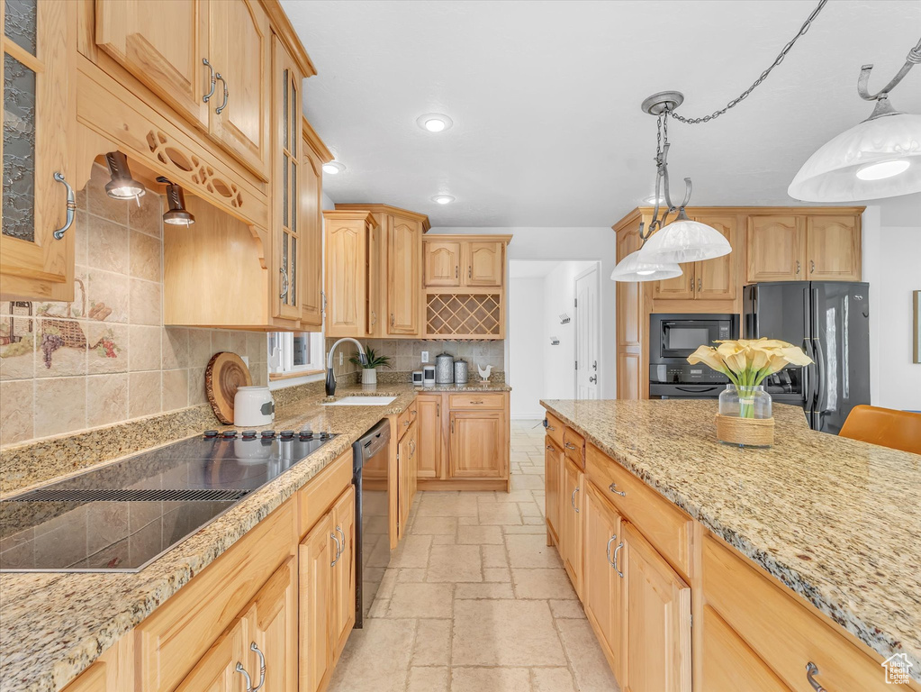 Kitchen featuring black appliances, a sink, stone tile floors, decorative backsplash, and glass insert cabinets