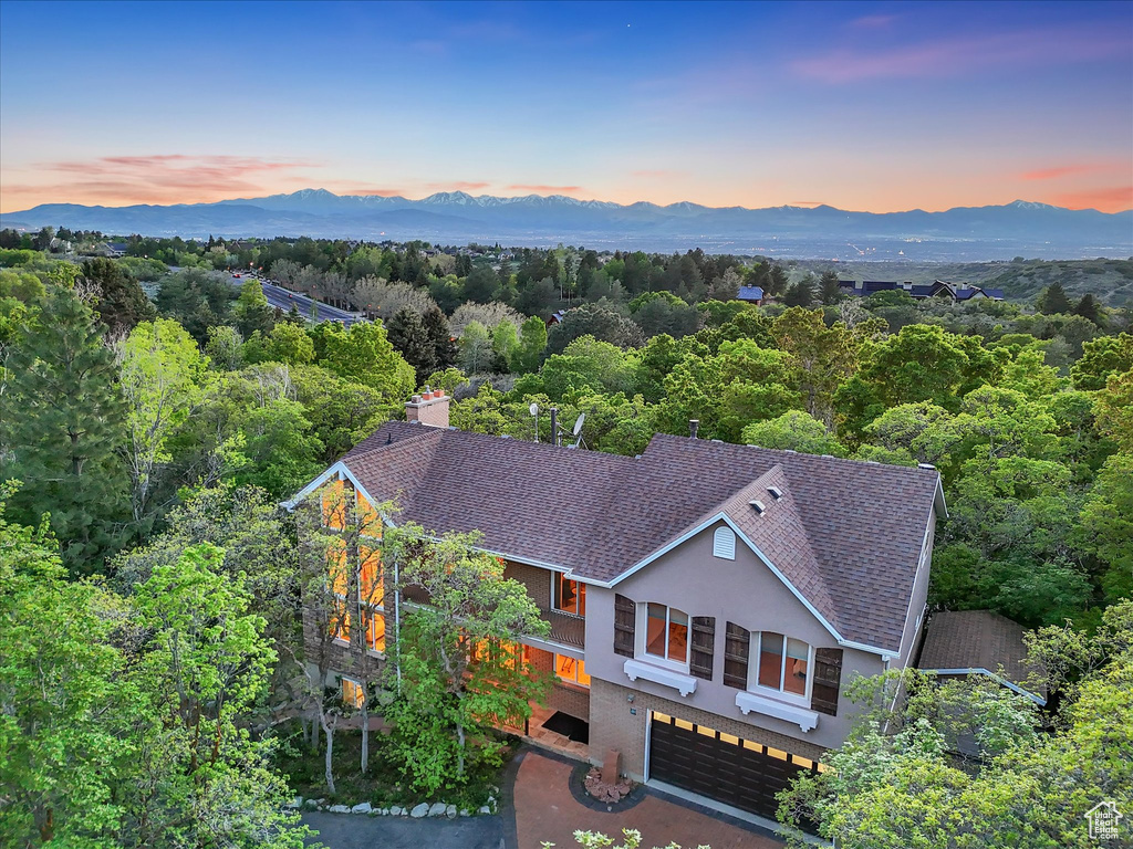 Aerial view of property and surrounding area featuring a mountainous background and a forest