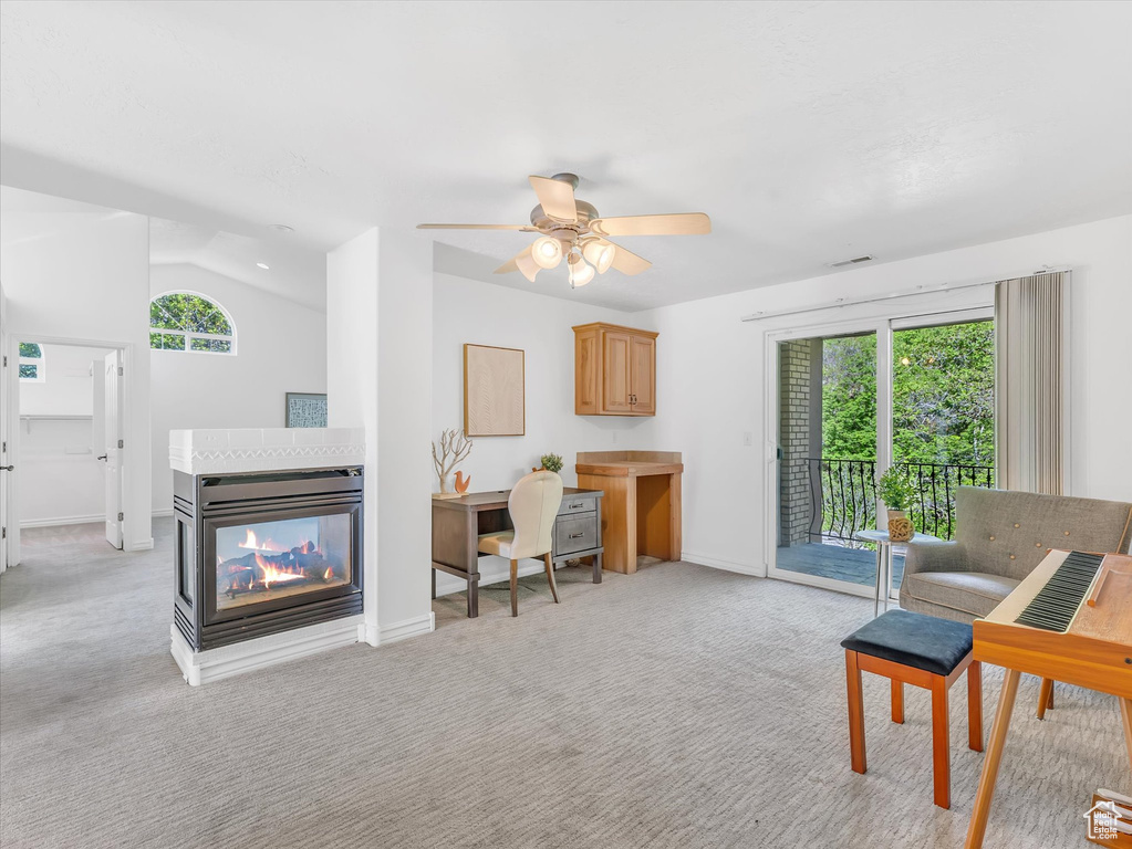 Living room with light carpet, a multi sided fireplace, ceiling fan, baseboards, and vaulted ceiling