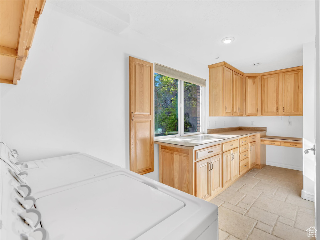 Kitchen with stone tile floors, washer / dryer, light brown cabinets, light countertops, and recessed lighting