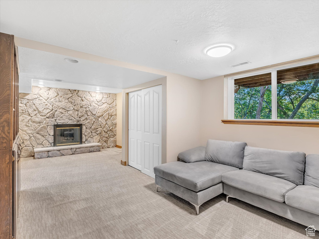 Living area with light carpet, a fireplace, and a textured ceiling