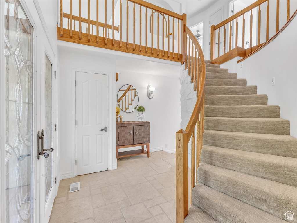 Stairway featuring stone tile floors, a high ceiling, and baseboards