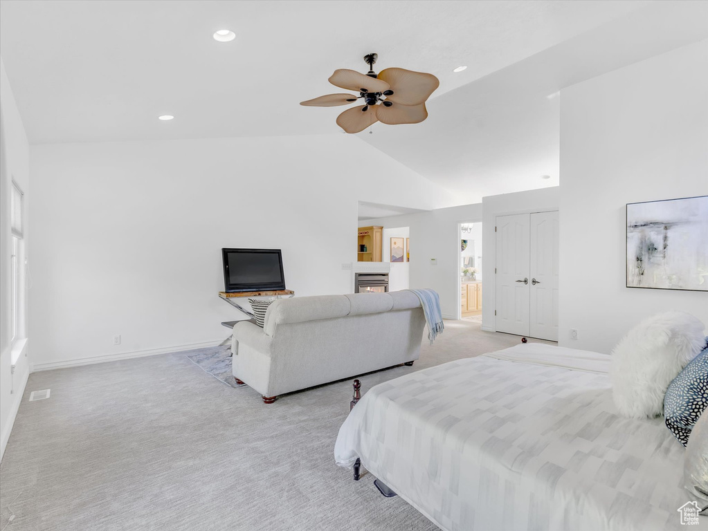 Bedroom with light carpet, vaulted ceiling, a glass covered fireplace, recessed lighting, and baseboards