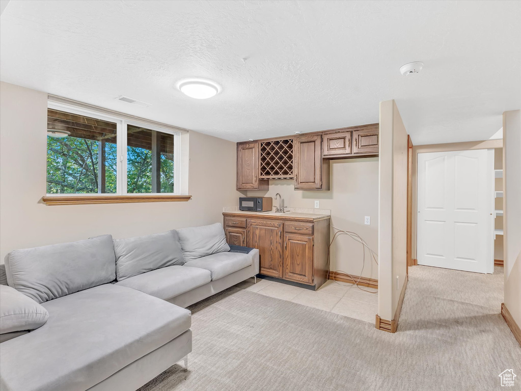 Living area with wet bar, baseboards, light tile patterned flooring, and a textured ceiling