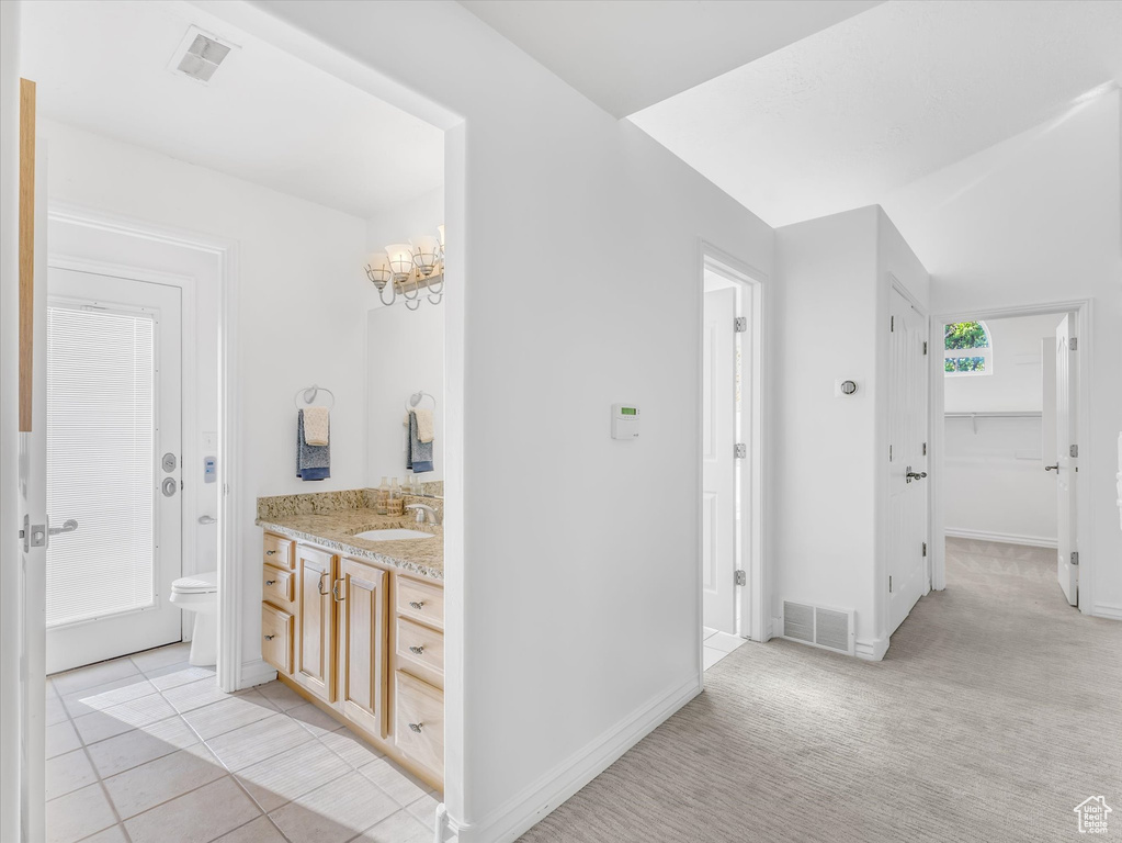 Bathroom featuring vanity, a chandelier, baseboards, toilet, and tile patterned floors