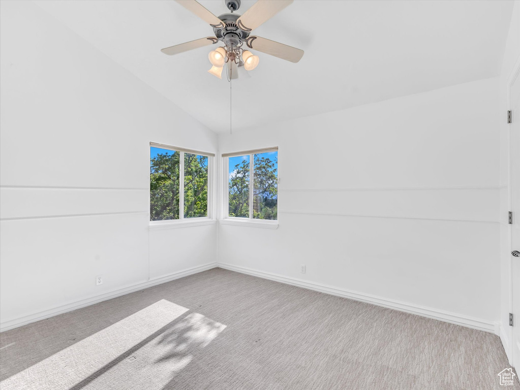 Spare room featuring carpet floors, a ceiling fan, lofted ceiling, and baseboards