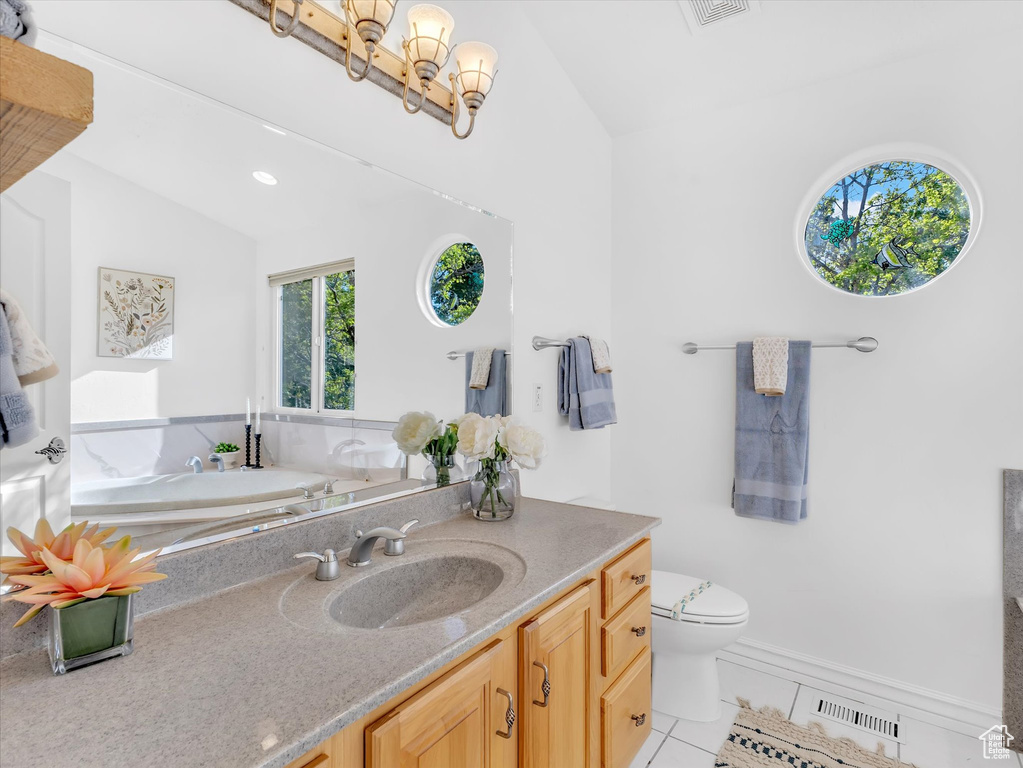 Bathroom featuring tile patterned floors, lofted ceiling, toilet, a chandelier, and vanity