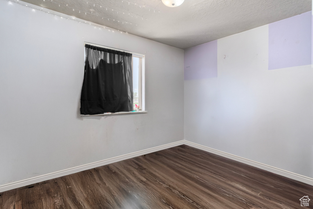 Unfurnished room with wood finished floors, baseboards, and a textured ceiling