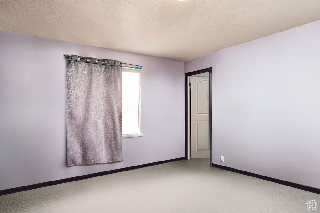 Carpeted spare room with baseboards and a textured ceiling