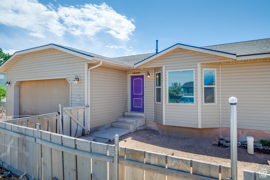View of front of house featuring roof with shingles, a garage, concrete driveway, and a gate