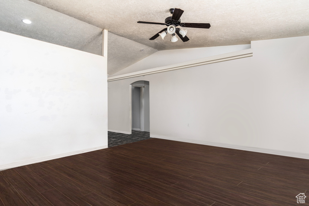 Empty room featuring a ceiling fan, wood finished floors, arched walkways, vaulted ceiling, and recessed lighting